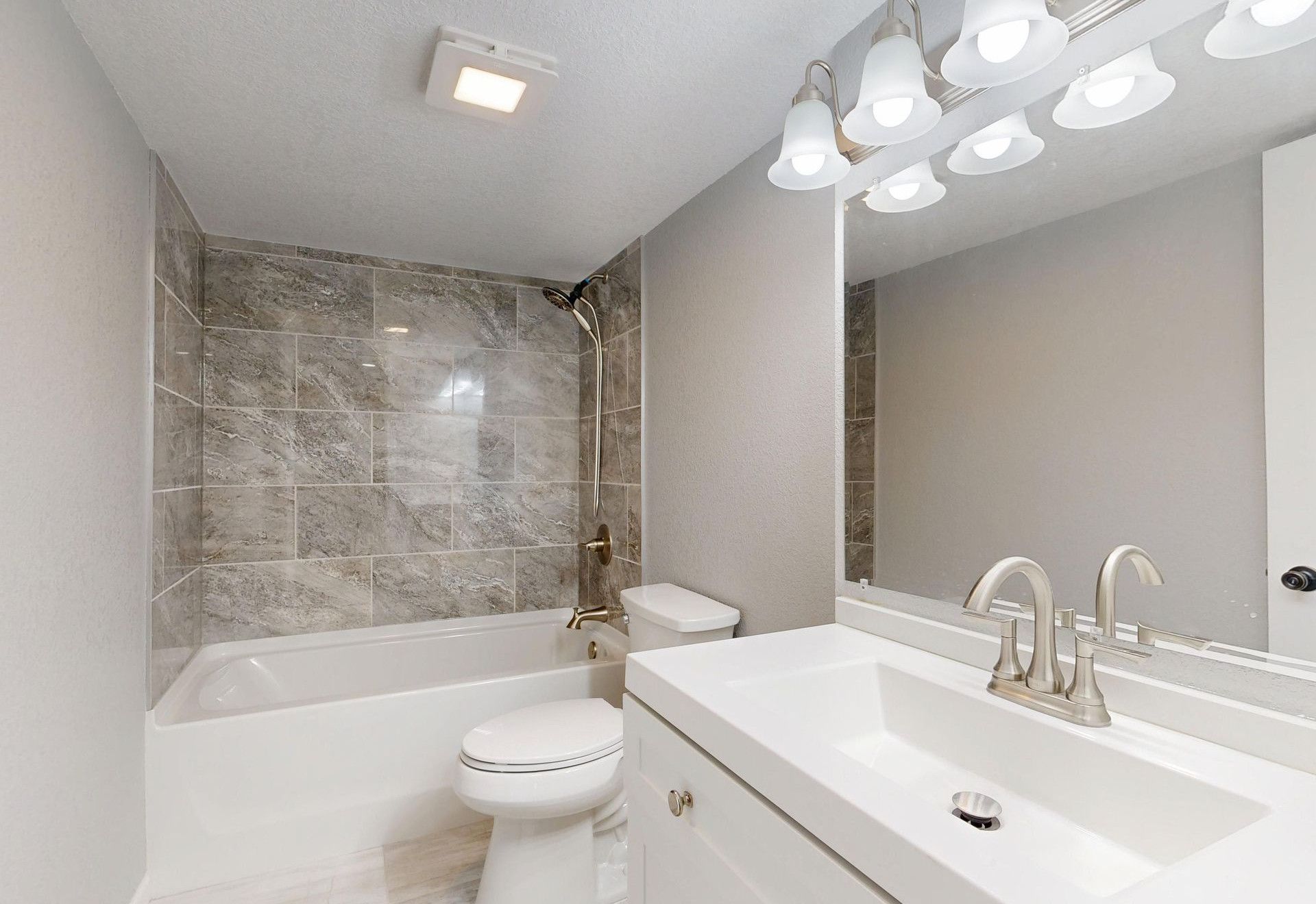 Elegant modern bathroom featuring marble tiles and sleek white vanity.