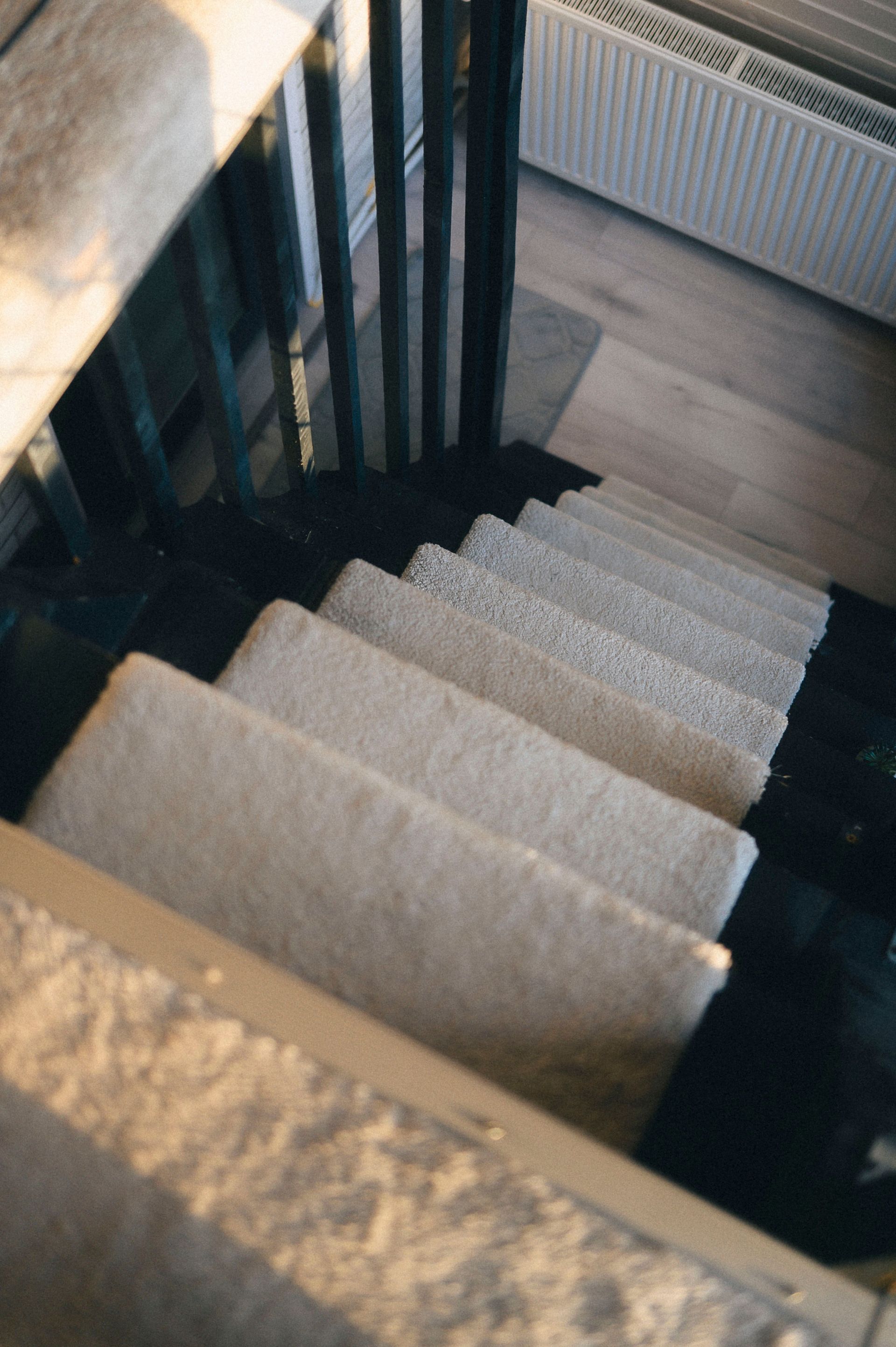A close-up view of carpeted stairs with sleek railing in a modern home interior.